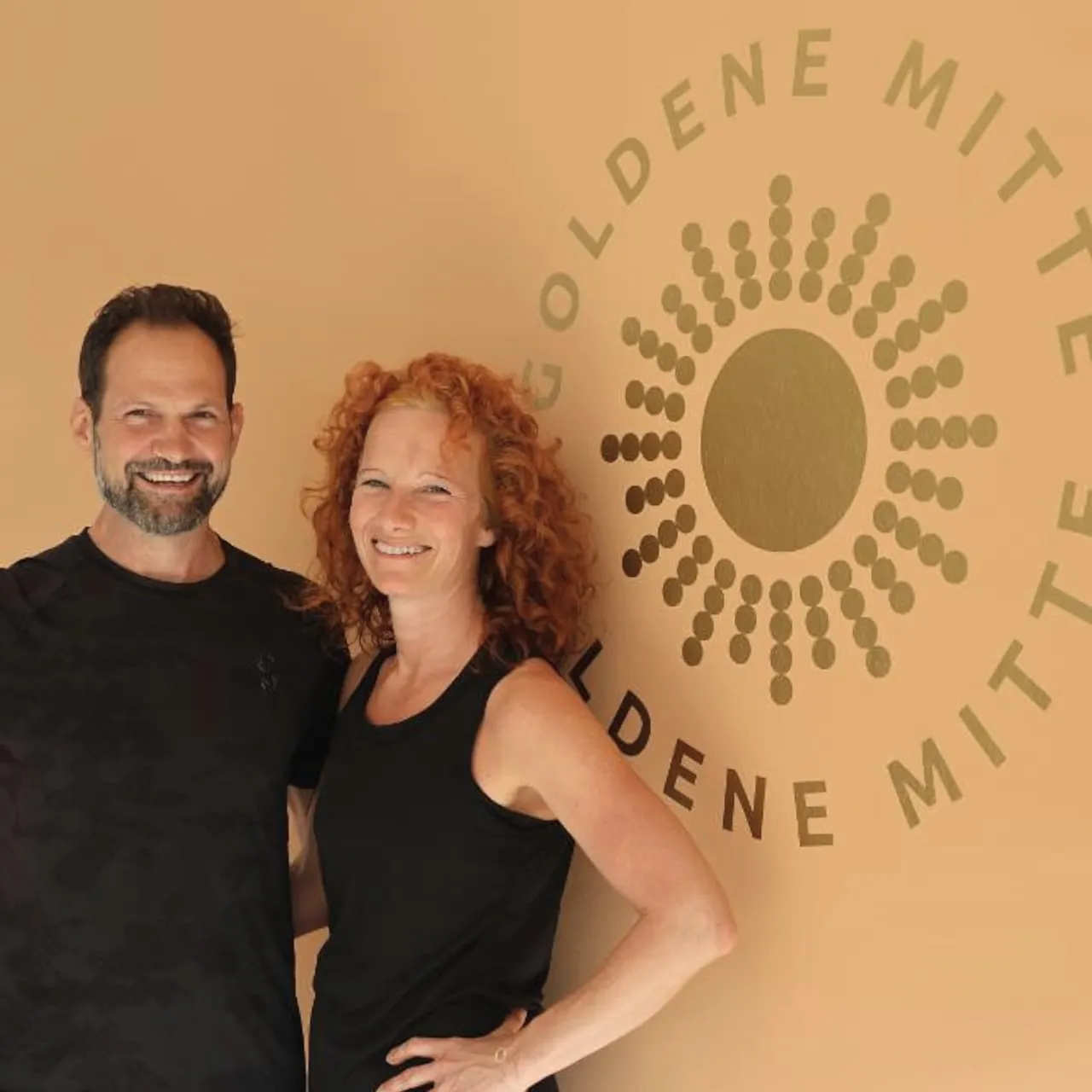 Tanja Hiebler und ihr Lebensgefährte Thomas vor dem Logo ihres Pilates-Studios Goldene Mitte